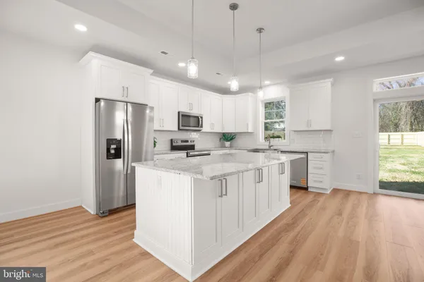 a large white kitchen with kitchen island a stove a sink dishwasher and a oven with white cabinets