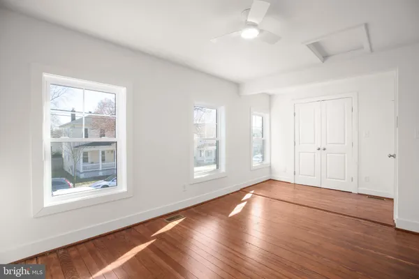 a view of empty room with wooden floor and fan