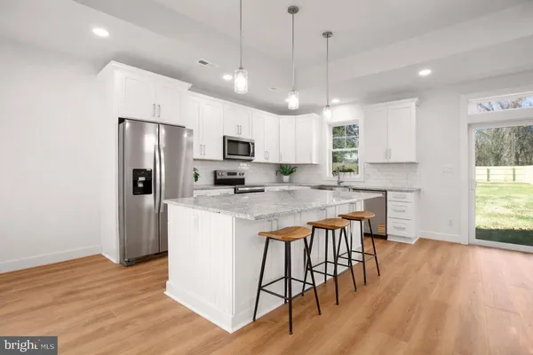 a kitchen with kitchen island granite countertop a center island a sink stainless steel appliances and cabinets
