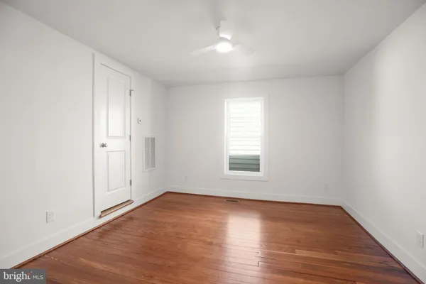 an empty room with wooden floor and fan