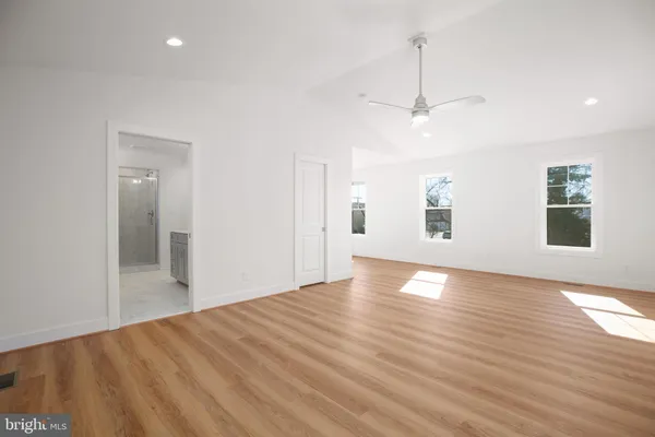 an empty room with wooden floor windows and ceiling fan