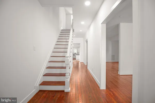 a view of a hallway with wooden floor and staircase