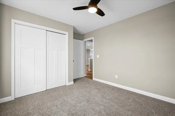 an empty room with a ceiling fan and carpet