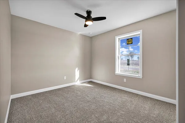 an empty room with ceiling fan and windows