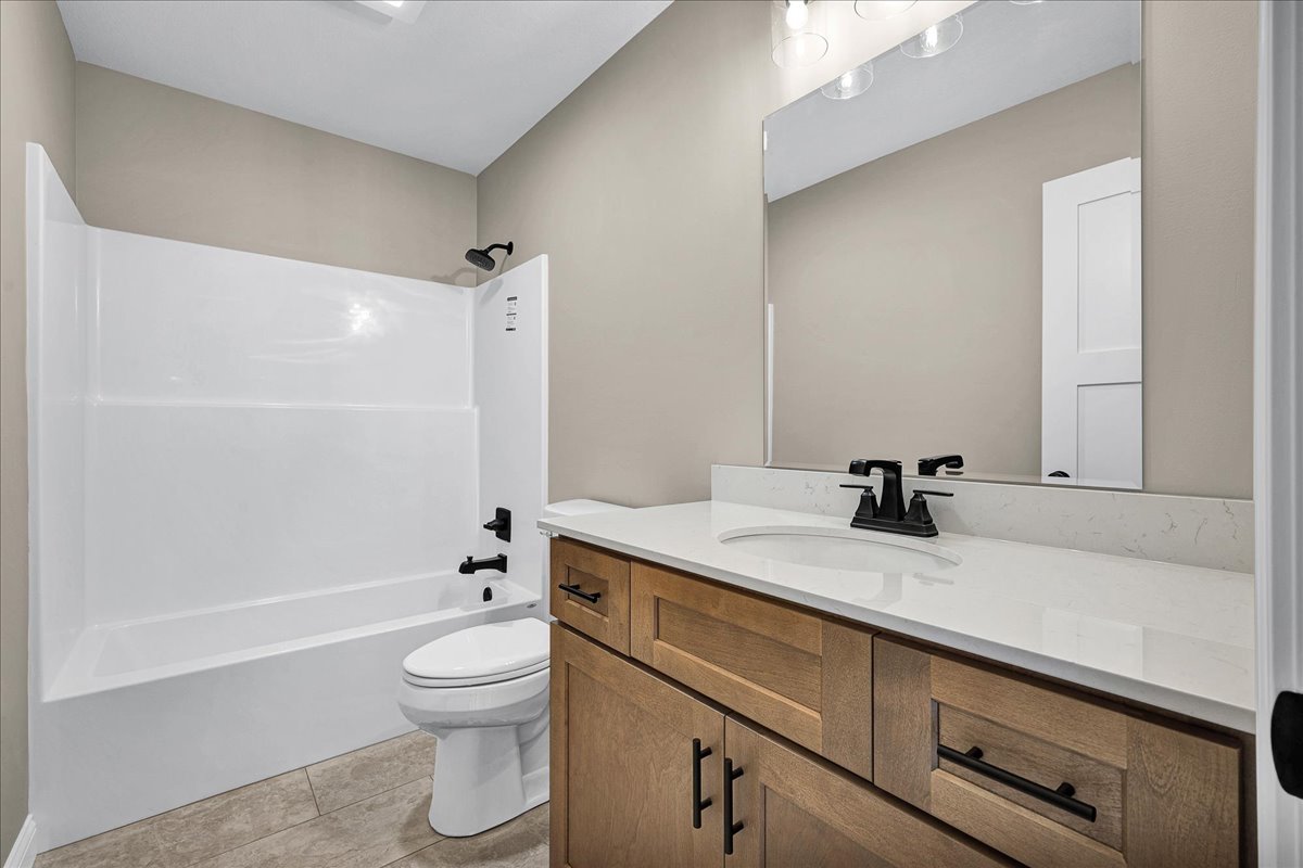 180 South Oak Street El Paso, IL 61738 - Photo 22 of 32 a bathroom with a granite countertop sink toilet a large mirror a bathtub and shower