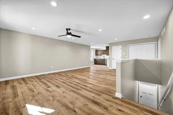 a view of kitchen and empty room with wooden floor