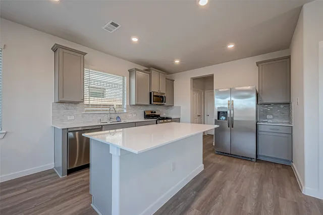 a kitchen with stainless steel appliances granite countertop a stove a sink and a refrigerator