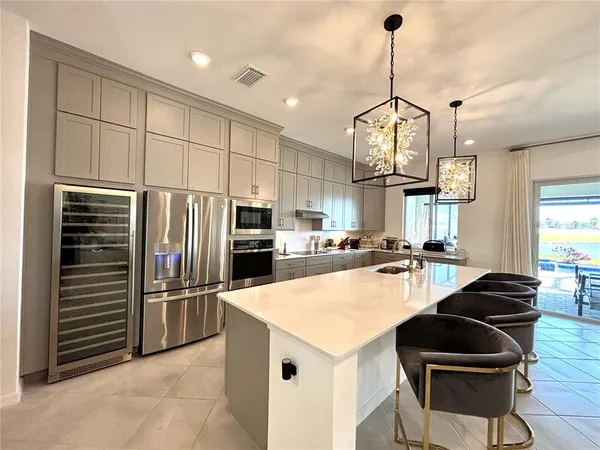 a kitchen with granite countertop a refrigerator a stove a sink and chairs