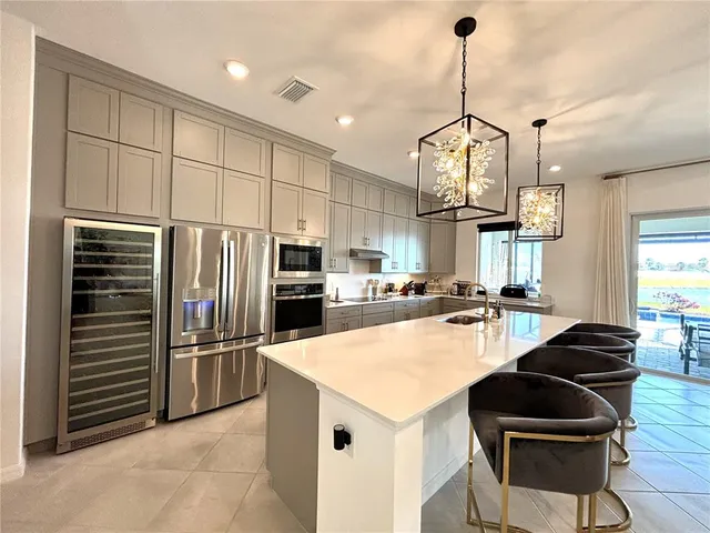 a kitchen with granite countertop a refrigerator a stove a sink and chairs