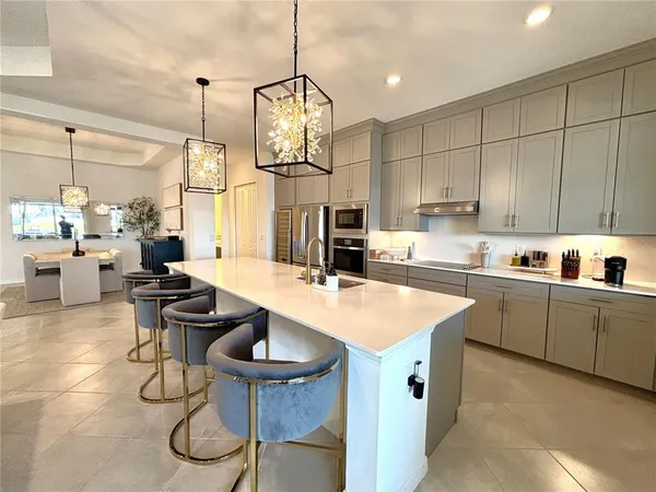 a kitchen with stainless steel appliances granite countertop a sink a stove and chairs