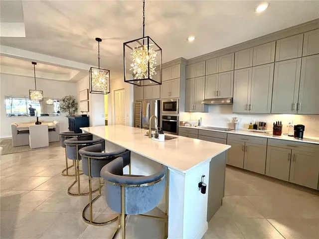 a kitchen with stainless steel appliances granite countertop a sink a stove and chairs