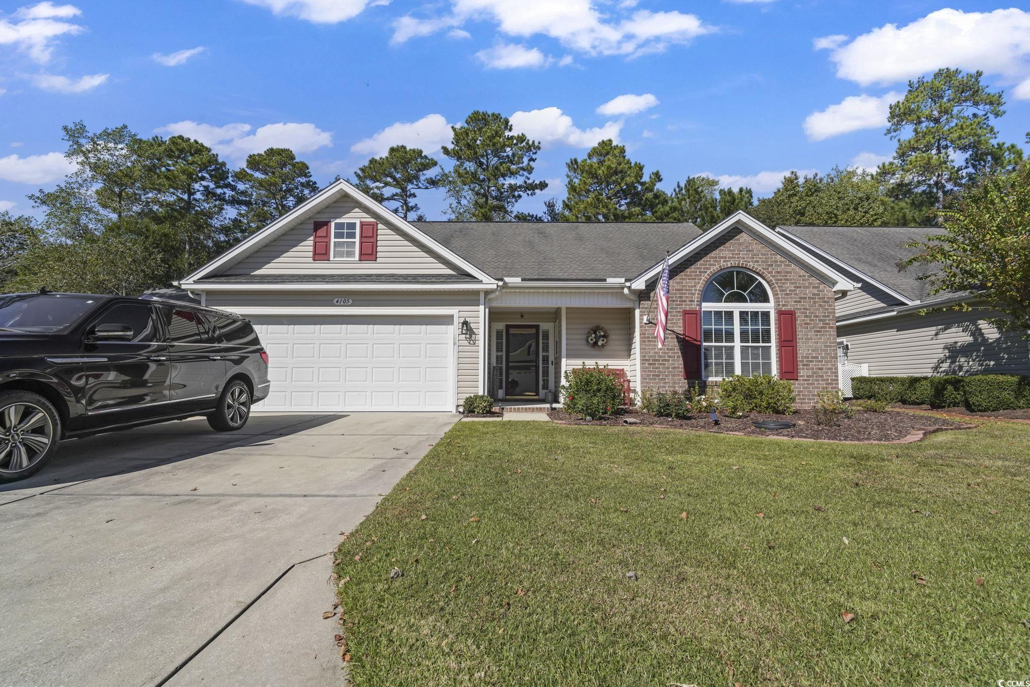 Ranch-style house with driveway, a front lawn, covered porch, a shingled roof, and brick siding