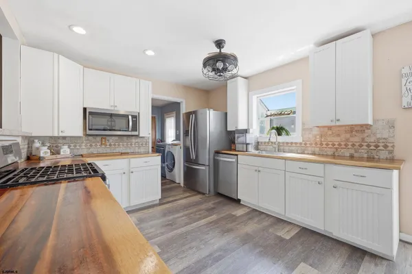 a kitchen with a refrigerator a sink dishwasher a stove and white cabinets with wooden floor