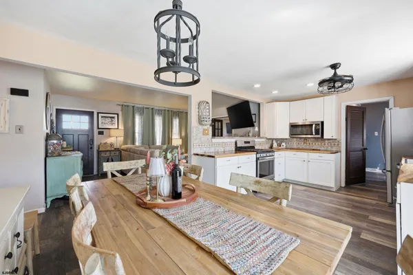 a living room with stainless steel appliances kitchen island granite countertop furniture a rug kitchen view and a chandelier