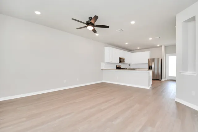 a view of a kitchen with kitchen island a sink wooden floor and a refrigerator