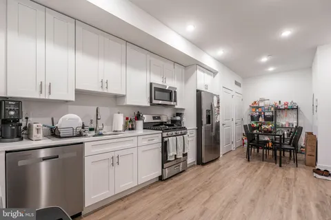 a kitchen with granite countertop a sink cabinets stainless steel appliances and dining table