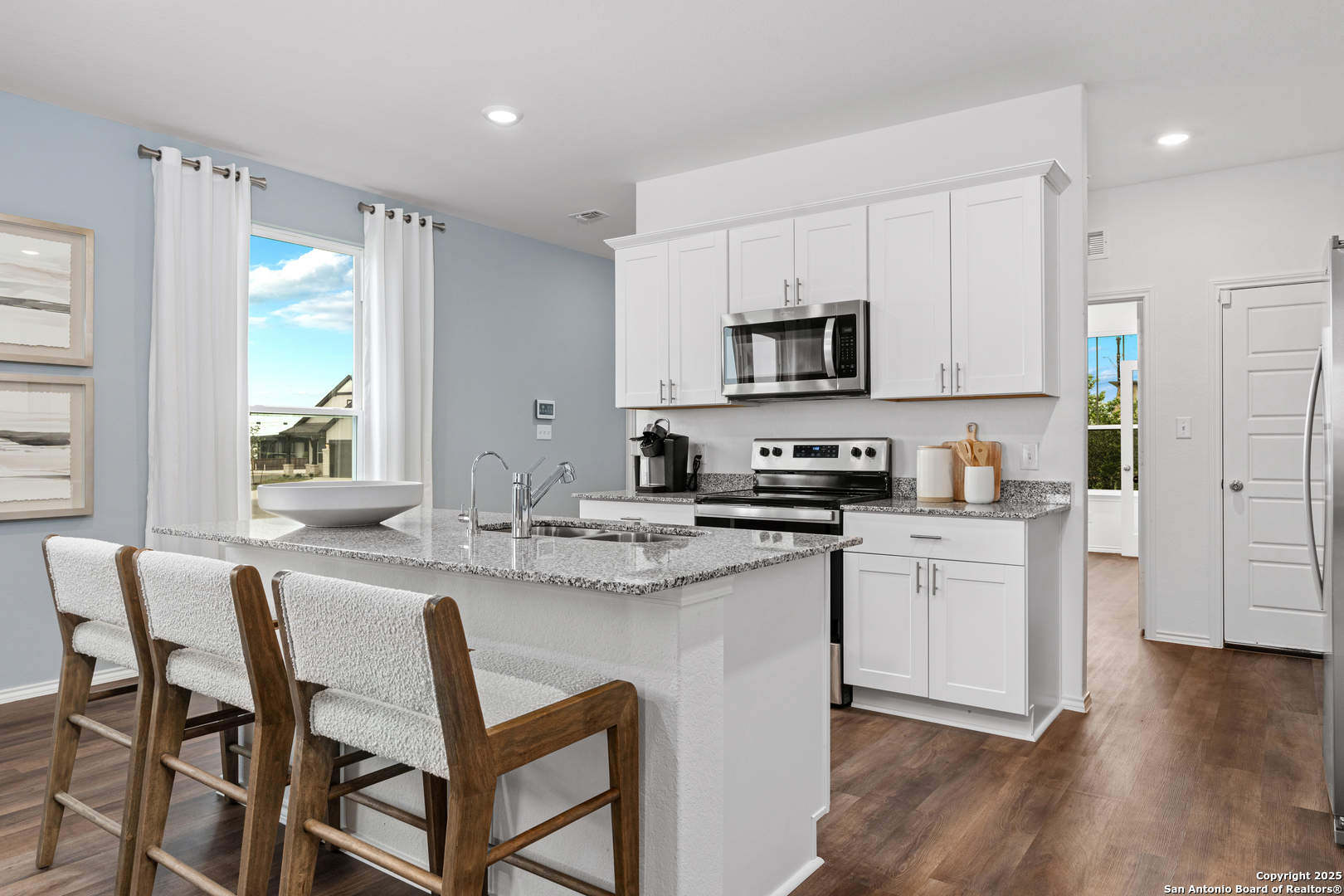405 Raven Row Marion, TX 78124 - Photo 10 of 25 a kitchen with stainless steel appliances granite countertop a stove a sink a microwave a refrigerator and white cabinets with wooden floor