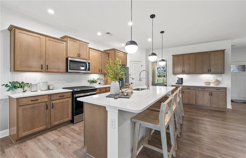 421 Beacon Way Villa Rica, GA 30180 - Photo 5 of 36 a kitchen with kitchen island granite countertop a sink a stove a microwave a center island and cabinets