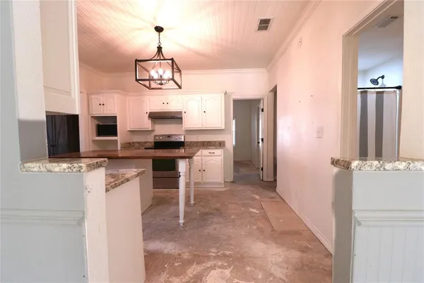 a view of a kitchen with granite countertop stainless steel appliances and a chandelier