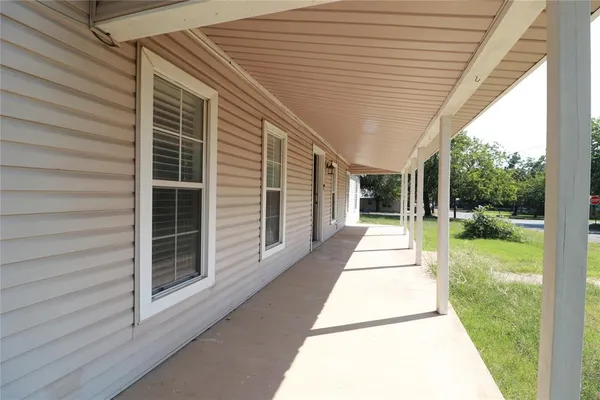a porch with a table and chairs next to a yard
