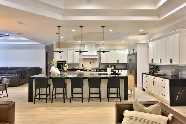 a kitchen with stainless steel appliances granite countertop a stove top oven a dining table and chairs with wooden floor