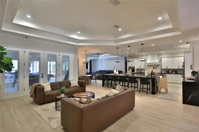 a living room with furniture kitchen view and a wooden floor