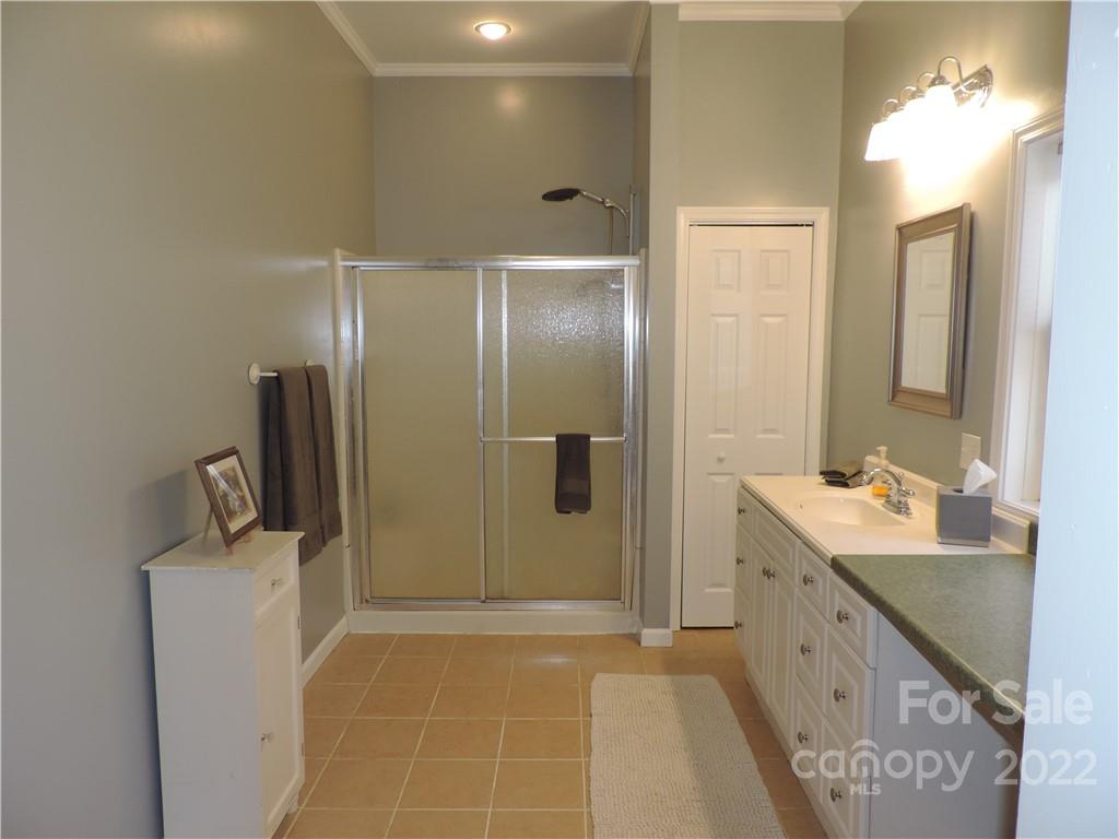3284 Lake Logan Road Canton, NC 28716 - Photo 16 of 44 a bathroom with a double vanity sink a mirror and a shower