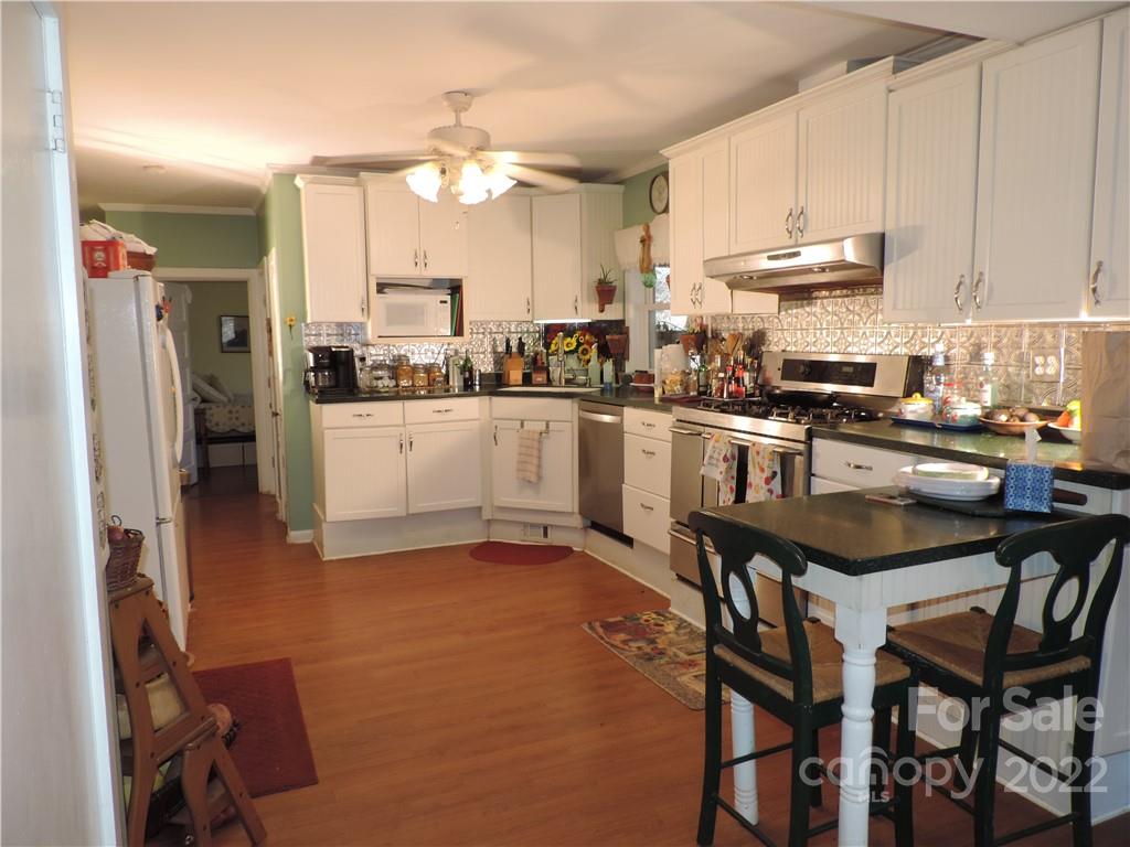 3284 Lake Logan Road Canton, NC 28716 - Photo 4 of 44 a kitchen with stainless steel appliances kitchen island granite countertop a table chairs sink and cabinets