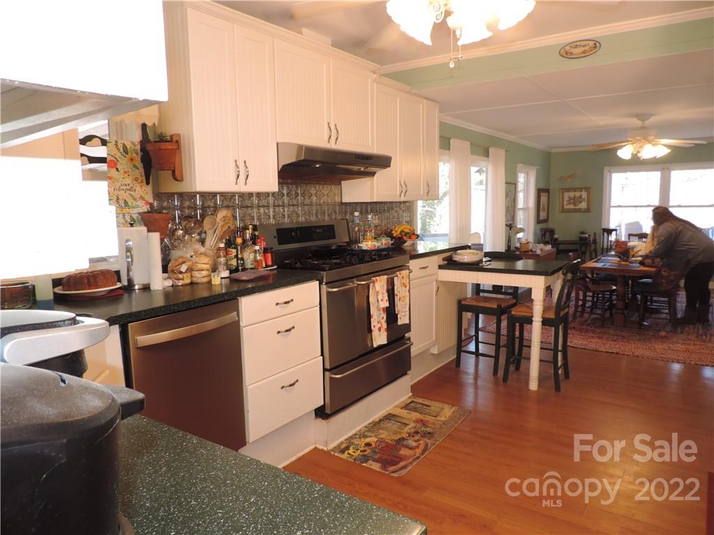 3284 Lake Logan Road Canton, NC 28716 - Photo 5 of 44 a kitchen with stainless steel appliances granite countertop a stove top oven a sink a dining table and chairs with wooden floor