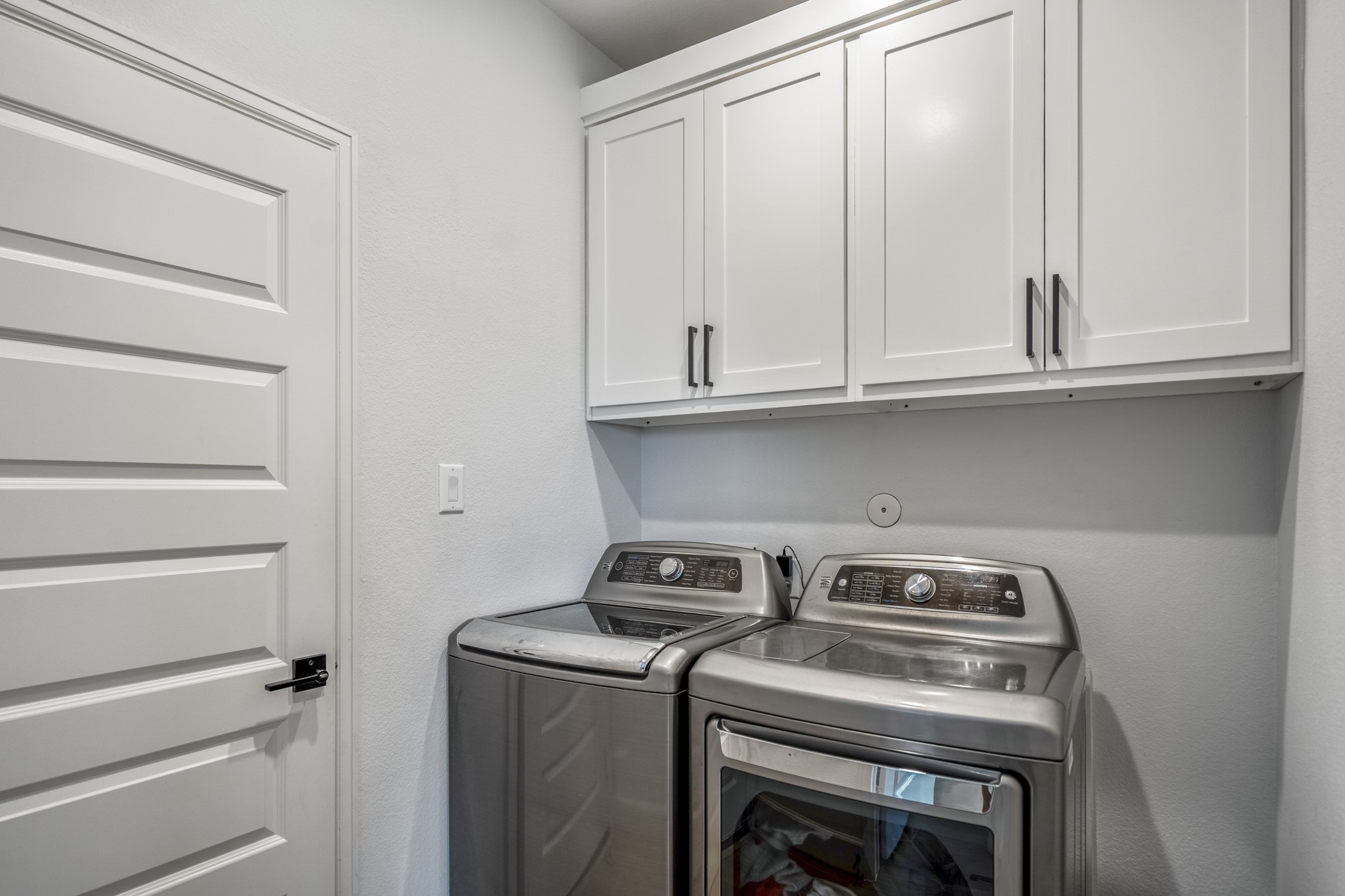 304 Mullins Court Montgomery, TX 77316 - Photo 18 of 50 This laundry room features sleek white cabinets for storage and a clean, minimalistic design.