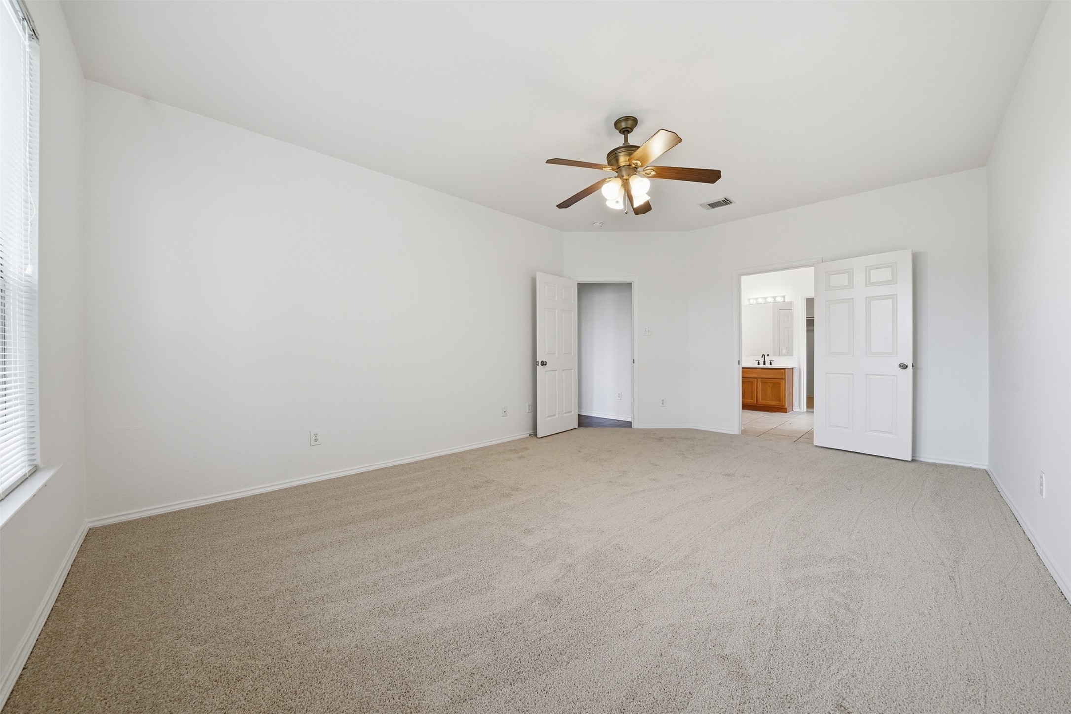 118 Invierno Street Kyle, TX 78640 - Photo 19 of 37 A spacious bedroom offers a tranquil retreat, featuring soft carpet and a convenient en-suite bathroom.