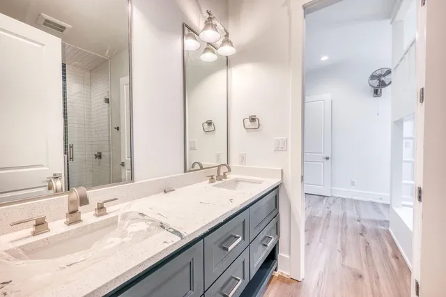 a bathroom with a granite countertop double vanity sink mirror and shower