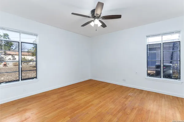 an empty room with windows and fan