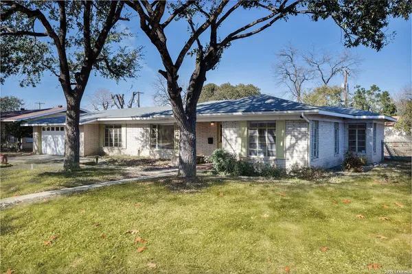 a view of a house with a large tree and a yard