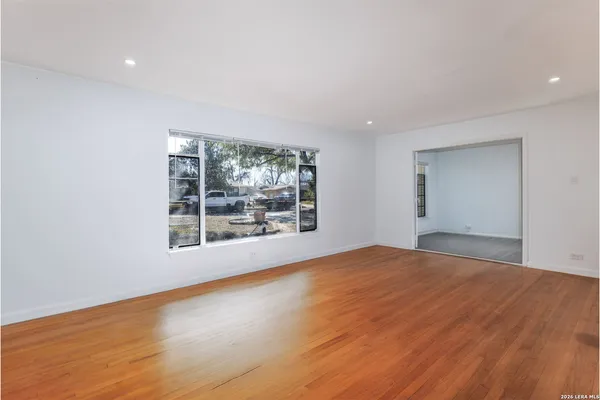 a view of an empty room with wooden floor and a window