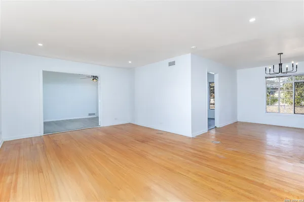 a view of an empty room with window and wooden floor