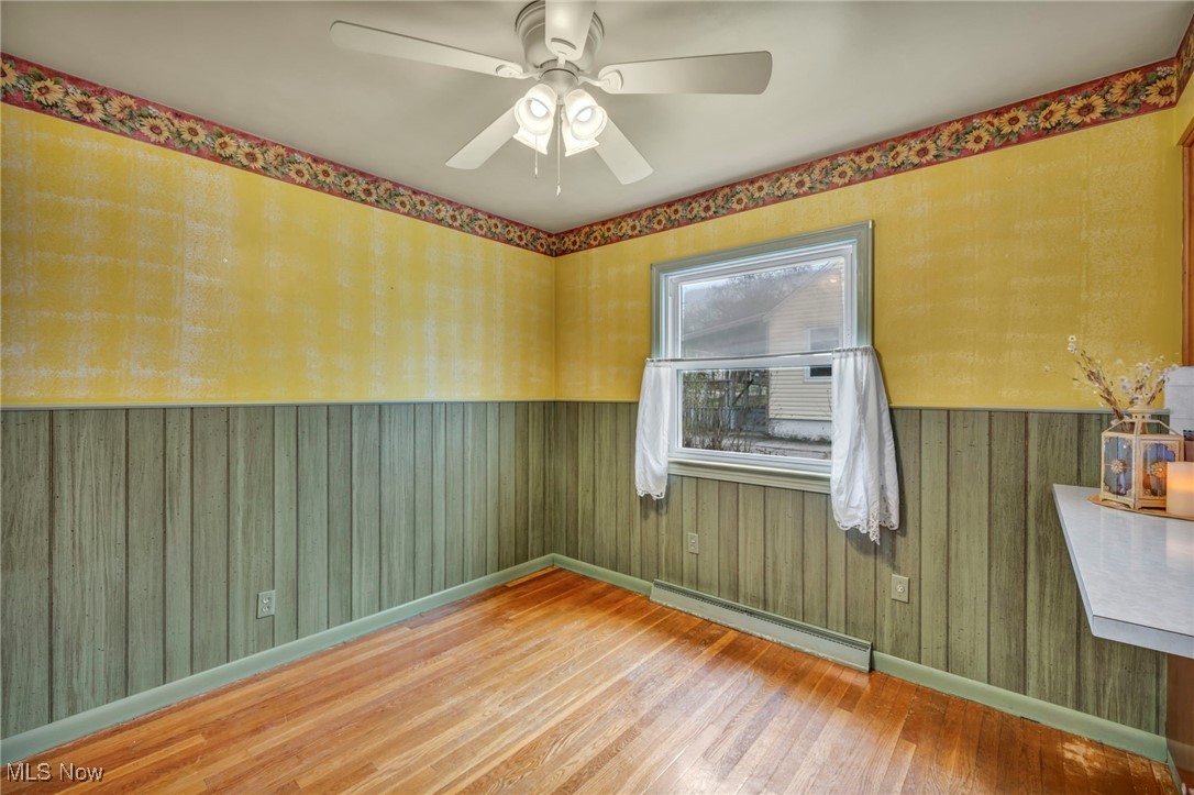 367 High Grove Boulevard Akron, OH 44312 - Photo 13 of 46 Unfurnished room featuring a wainscoted wall, a ceiling fan, baseboard heating, baseboards, and hardwood / wood-style flooring