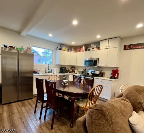 a kitchen with stainless steel appliances granite countertop a dining table chairs refrigerator and microwave