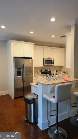 a kitchen with kitchen island stainless steel appliances a sink a stove a refrigerator cabinets and a dining table