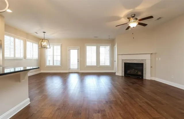 an empty room with wooden floor fireplace and windows