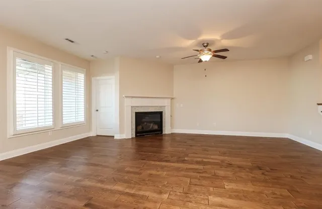 an empty room with windows chandelier fan and fireplace