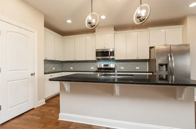 a kitchen with stainless steel appliances granite countertop a sink a stove and a refrigerator