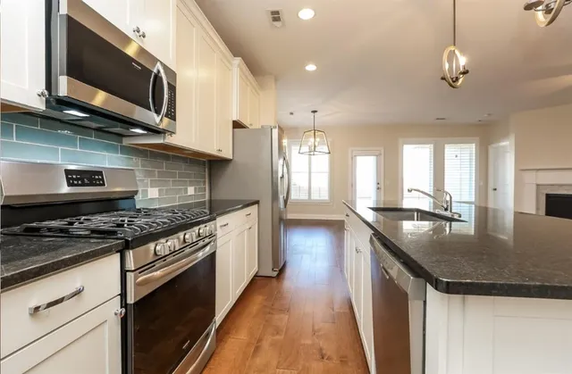 a kitchen with stainless steel appliances granite countertop a stove a sink and a microwave
