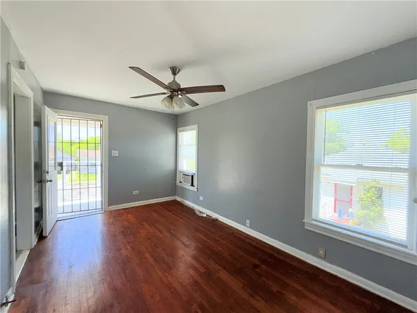 a view of an empty room with a window and wooden floor