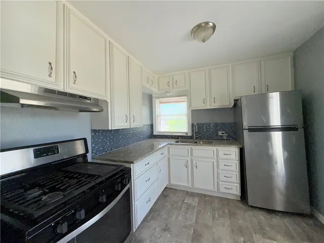 a kitchen with white cabinets and appliances