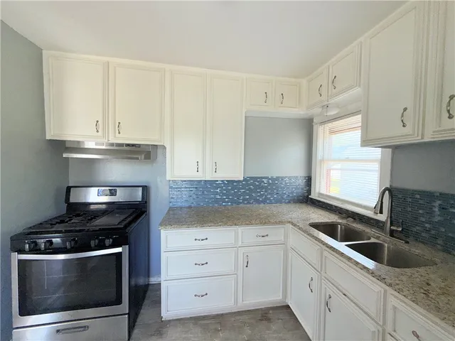 a kitchen with granite countertop white cabinets and stainless steel appliances