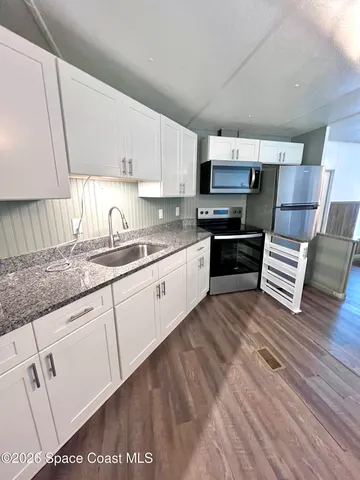 a kitchen with granite countertop a sink cabinets and wooden floor
