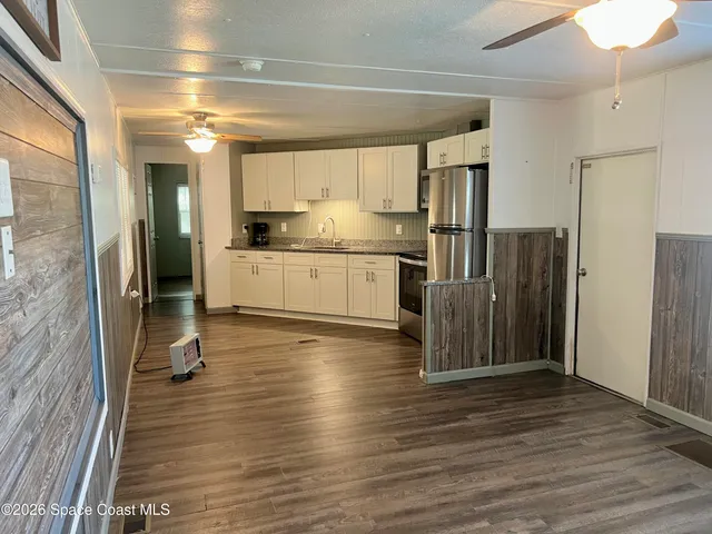 a kitchen with granite countertop a refrigerator and wooden floor