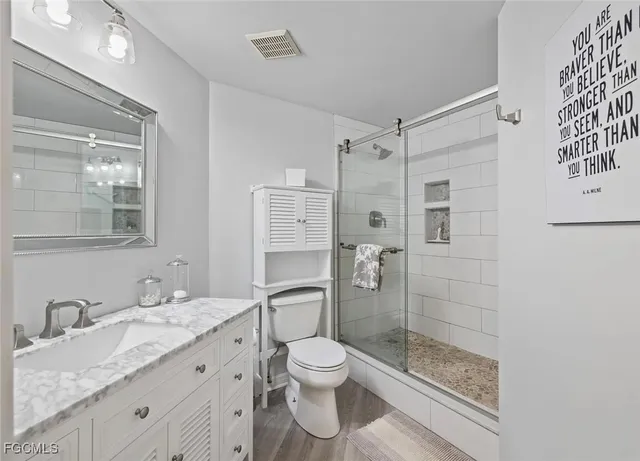 a bathroom with a granite countertop sink toilet a mirror and shower