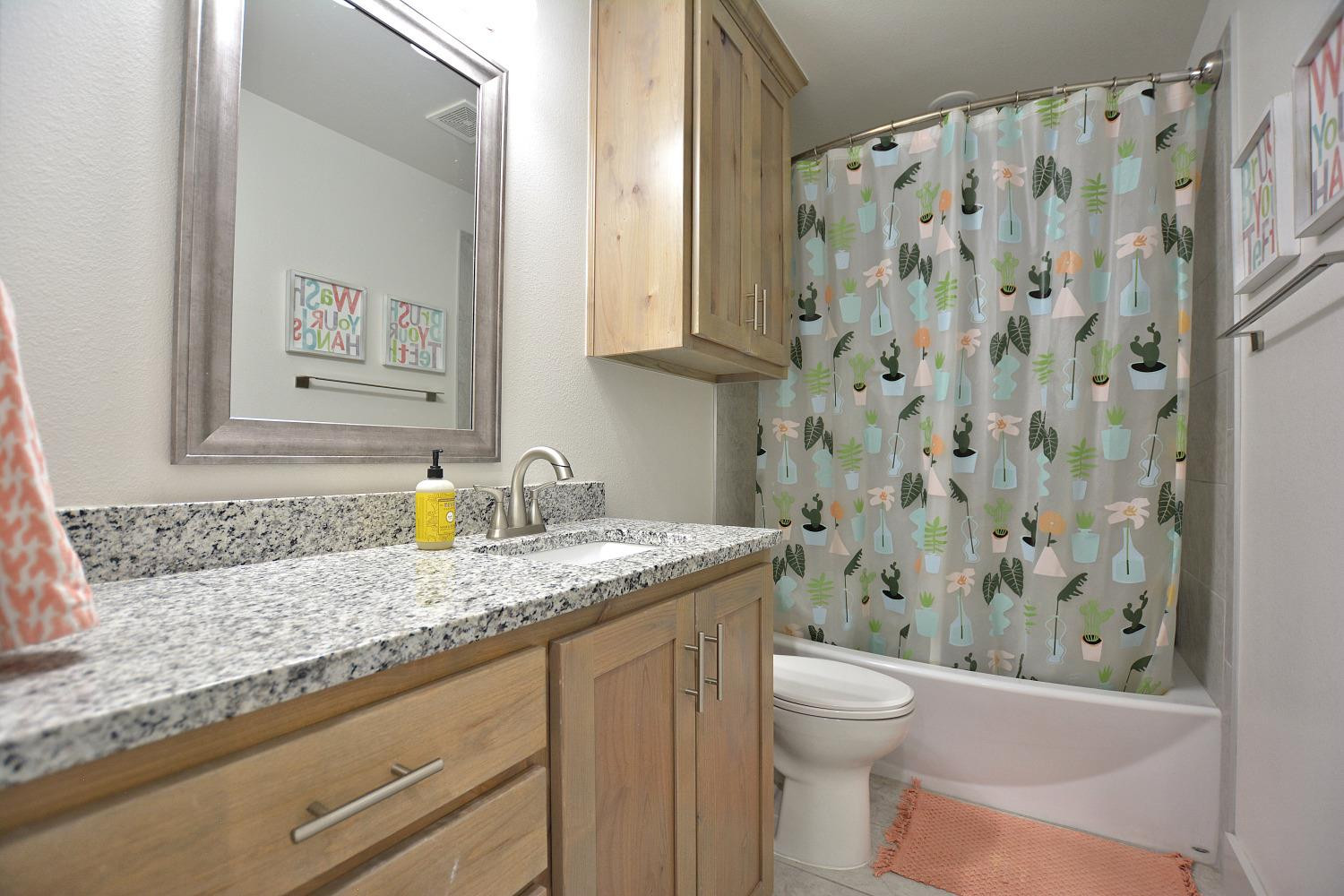 8901 Winfield Avenue Lubbock, TX 79424 - Photo 19 of 22 a bathroom with a granite countertop sink a toilet and a shower curtain